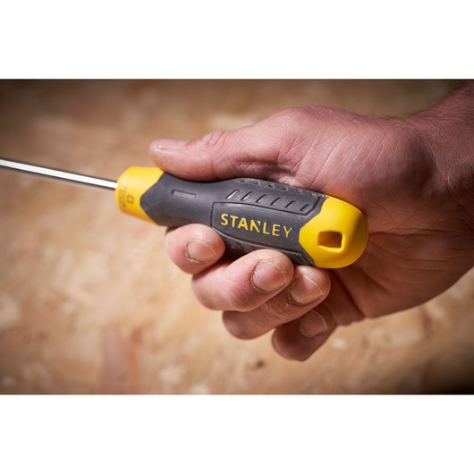 STANLEY STHT0-65153 screwdriver with yellow and black handle held in a hand, close-up side view.