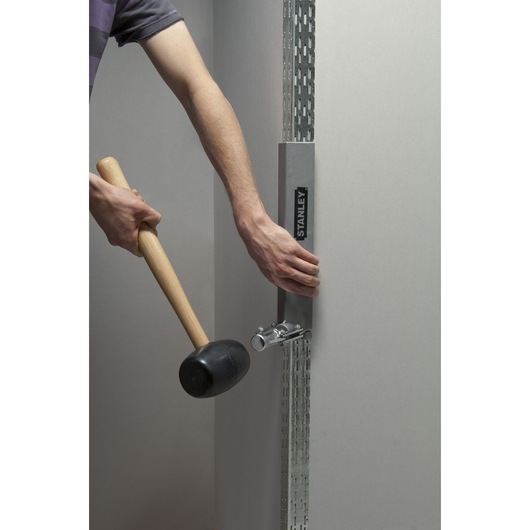 Photo of STANLEY STHT1-16132 tool in use for drywall installation, held against metal frame.