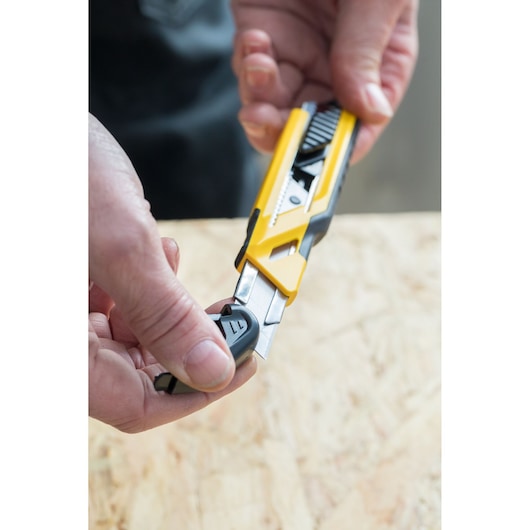 STANLEY STHT10266-1 utility knife with yellow and black handle held in hand, blade partially extended.