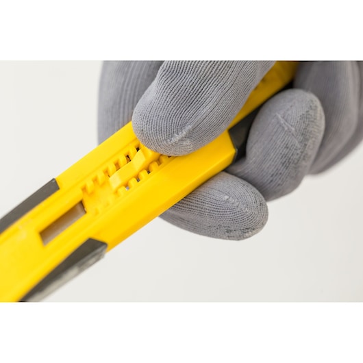 Photo of STANLEY STHT10345-0 utility knife, yellow body, close-up, held by a gloved hand.