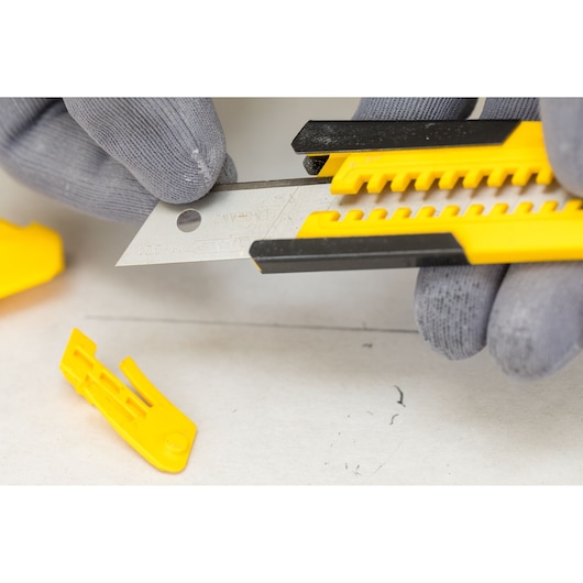 Photo of STANLEY STHT10345-0 utility knife with a segmented blade, being held by gloved hands during blade change.