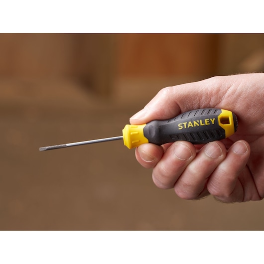 Photo of STANLEY STHT16151-0 flathead screwdriver with black and yellow handle held in hand.