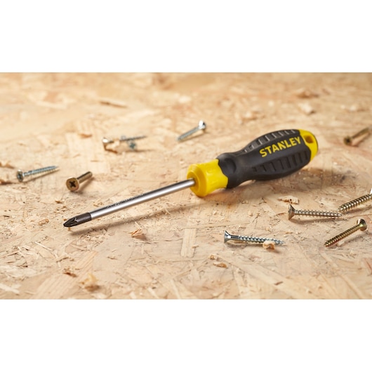 Stanley STHT16163-0 black and yellow Phillips screwdriver on wood with scattered screws.