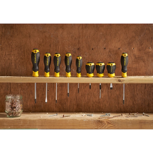STANLEY STHT16195-0 screwdriver set with black and yellow handles, lined up on a wooden shelf, front view.