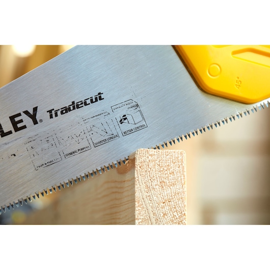 STANLEY STHT20348-1 hand saw with sharp teeth cutting wood, close-up angle on blade and handle.