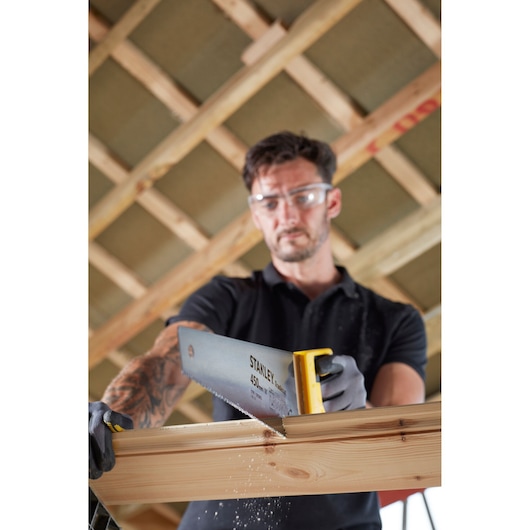 Photo of STANLEY STHT20355-1 handsaw with yellow handle, cutting wood beam indoors.
