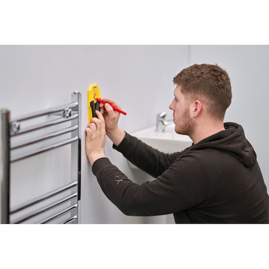 STANLEY STHT77588-0 wall marking tool used by person near sink and chrome towel rail.