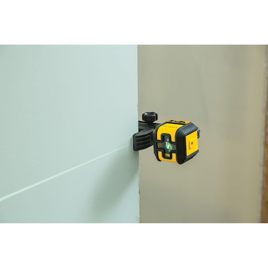 STANLEY STHT77649-1 laser level tool clamped to wall emitting green line, photography side angle.