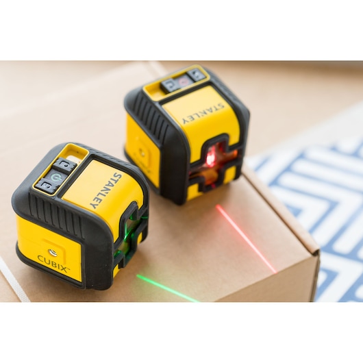 STANLEY STHT77649-1 laser level, yellow and black, front angle, emitting red and green laser lines.