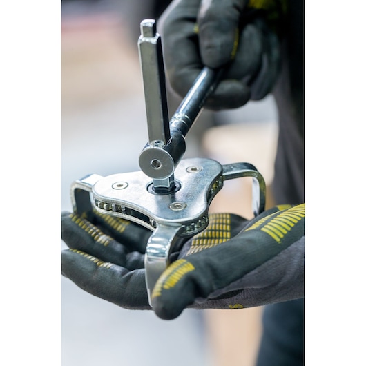 STANLEY STHT80880-0 three-jaw gear puller in use, close-up view held by gloved hands.
