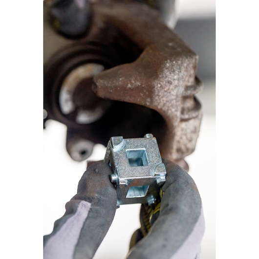 STANLEY STHT80883-0 cube socket tool held by gloved hand near automotive part, close-up photography.