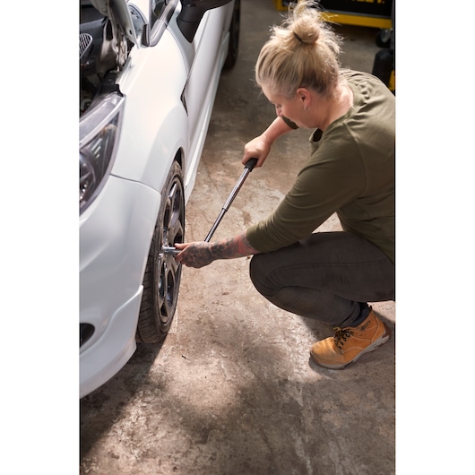 STANLEY STHT80890-0 torque wrench used on a car wheel by a person in a workshop.