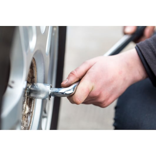 STANLEY STHT80890-0 hand using socket wrench on car wheel, close-up photo, automotive tool.