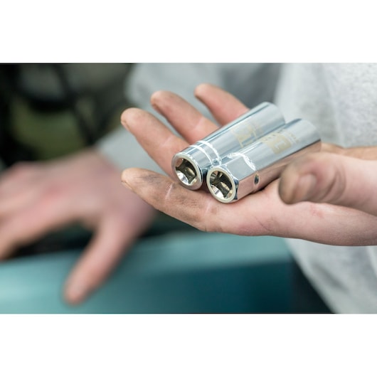 Photo of STANLEY STHT81582-0 chrome sockets held in a mechanic’s hand, close-up view.