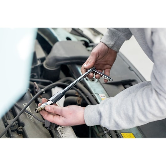 STANLEY STHT81583-0 T-handle socket wrench used on a car engine, side angle photography.