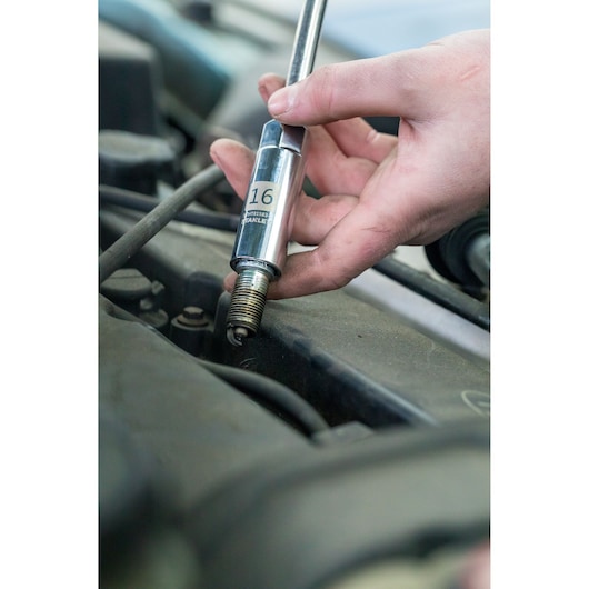 Photo of STANLEY STHT81583-0 socket wrench on a spark plug during car repair.