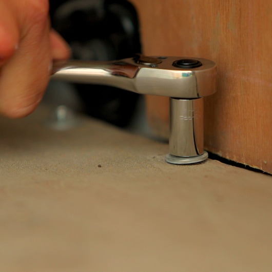 STANLEY STMT0-74864 ratchet wrench in use, close-up on socket fitting against a bolt near a wooden surface.