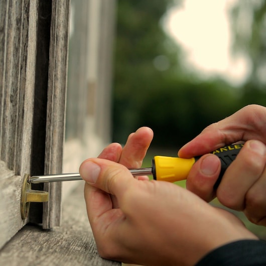 STANLEY STMT0-74864 screwdriver used to adjust window latch outdoors.