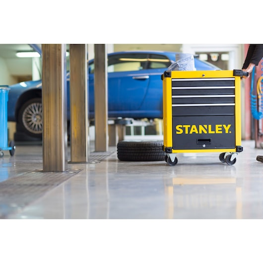 STANLEY STMT1-74305 tool chest with drawers on casters in a garage next to a blue car and tire.