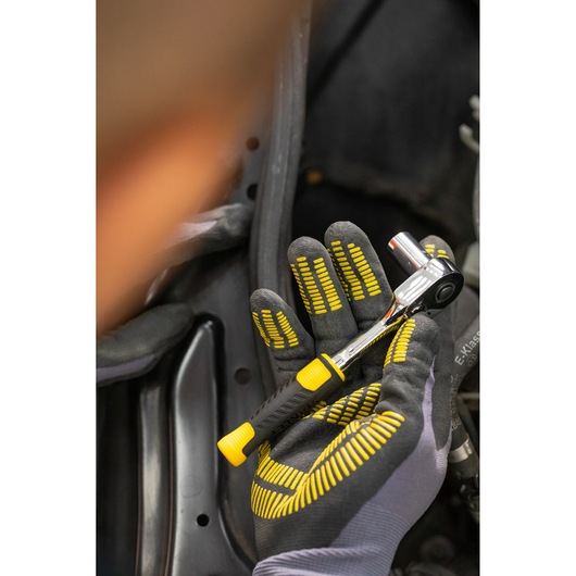 STANLEY STMT82663-0 ratchet wrench with yellow and black handle held in a gloved hand during use.