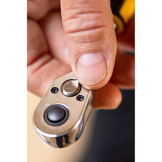 Close-up of hand using STANLEY STMT82663-0 ratchet wrench head, showing thumb pressing direction switch.