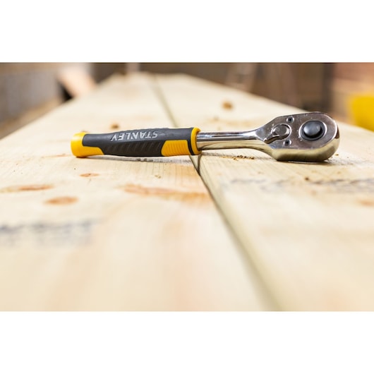 STANLEY STMT82664-0 ratchet wrench with black and yellow handle on wooden boards, close-up photography.