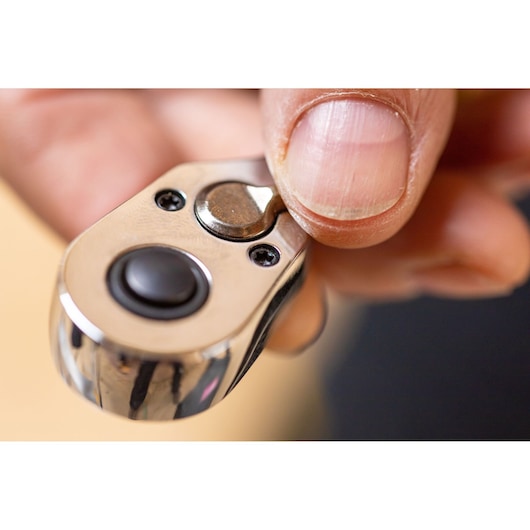 Close-up of STANLEY STMT82666-0 ratchet head with thumb pressing switch, photography of tool mechanism.