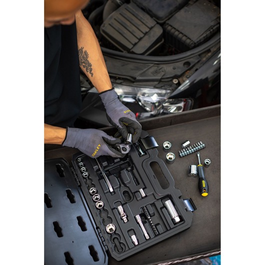 STANLEY STMT82828-1 socket set in black case, mechanic using tools near car engine, photography from above.
