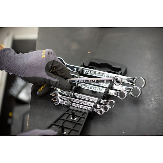 STANLEY STMT82842-0 chrome combination wrenches in holder, hand with glove selects tool, angled view.