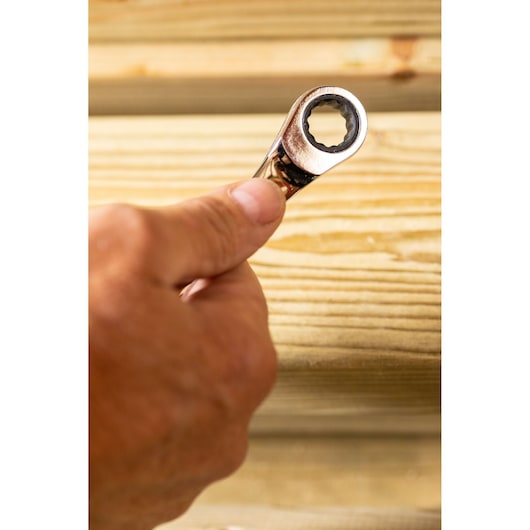 STANLEY STMT82847-0 ratcheting wrench held in hand, close-up against wooden planks.