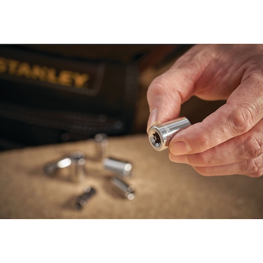STANLEY STMT86107-0 socket held in hand, several sockets on table, close-up photography.