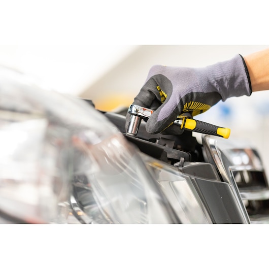 STANLEY STMT86108-0 ratchet wrench used on car headlight, close-up photography.