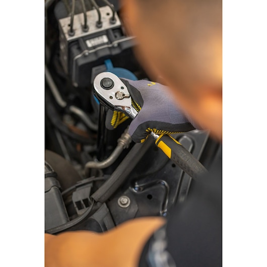 STANLEY STMT86206-0 ratchet used for car engine repair, close-up of gloved hand gripping black and yellow handle.