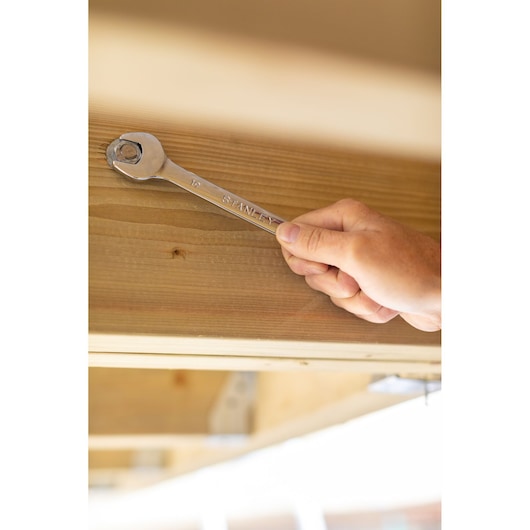 Stanley STMT95908-0 wrench held by hand on bolt, woodworking context, Photography category.