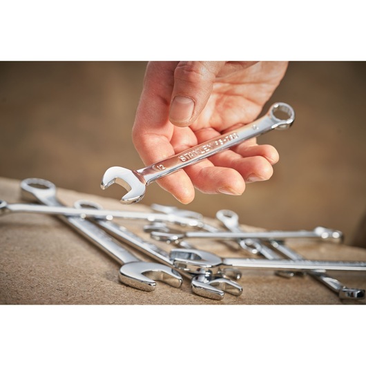 STANLEY STMT95909-0 combination wrench held in hand, with several chrome wrenches on a work surface.