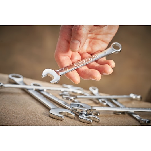 Photo of STANLEY STMT95911-0 wrench held in hand, with other chrome wrenches on a work surface.