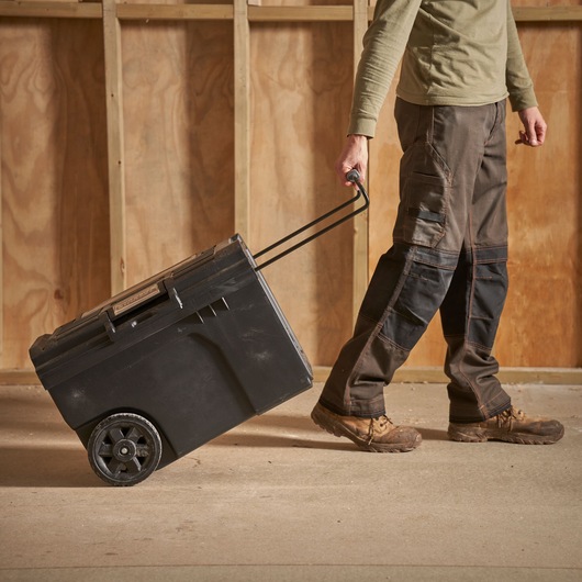 STANLEY STST1-70715 black wheeled toolbox being pulled by a person on a construction site.