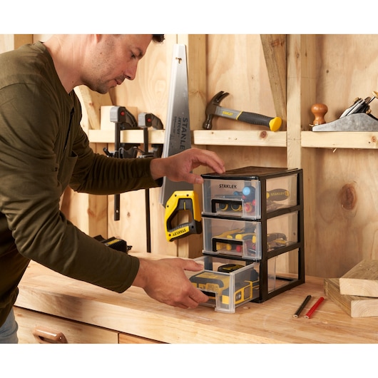 STANLEY STST40711-1 small parts organizer with three clear drawers on a workbench in a workshop.