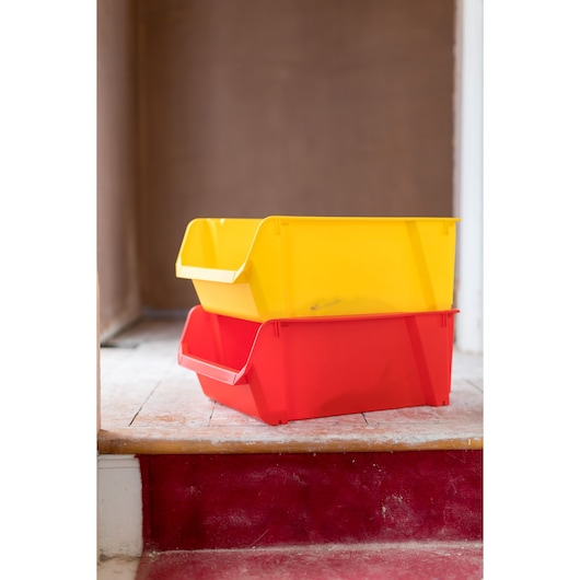 STANLEY STST70348-1 stackable storage bins, one yellow and one red, placed on wooden floor, side angle.