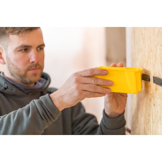 STANLEY STST82964-1 yellow tool being mounted on wooden wall, close-up photography.