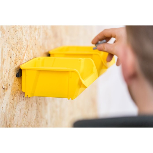 STANLEY STST82964-1 yellow storage bin attached to wall, person organizing small parts.