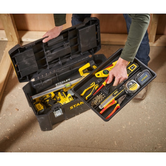 STANLEY STST82976-1 toolbox with open lid showing organized hand tools and accessories, workshop setting, top view.
