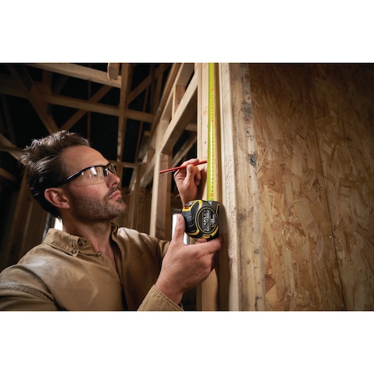 Photo of STANLEY XTHT0-33501 tape measure used to measure wooden frame during construction.