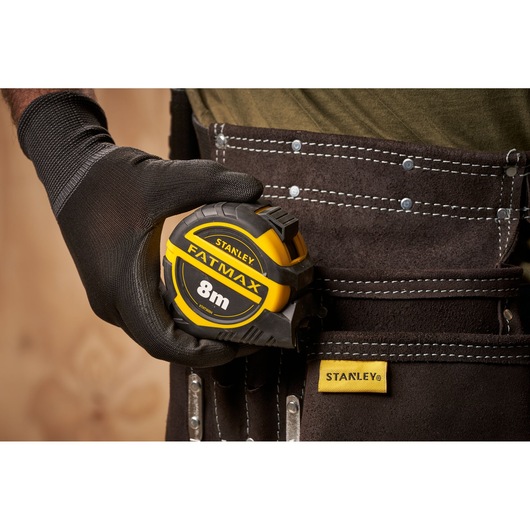 Photo of STANLEY XTHT0-36004 tape measure FATMAX 8m held by gloved hand on tool belt.