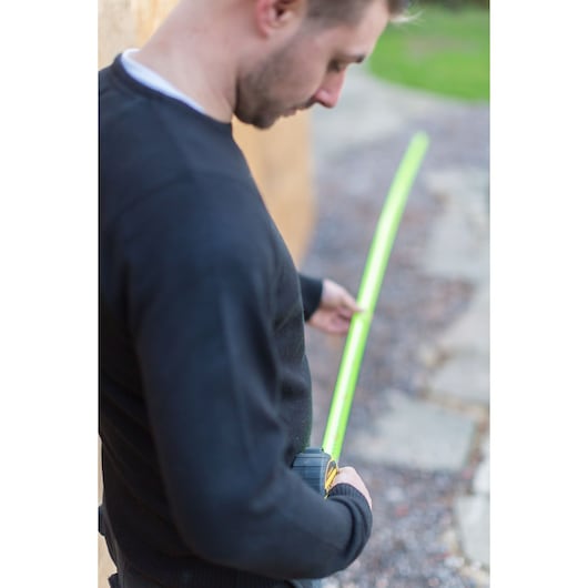 Person using STANLEY XTHT0-36005 tape measure outdoors along a path.