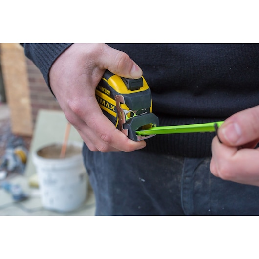 Photo of STANLEY XTHT0-36005 tape measure in use, yellow and black casing, close-up view.