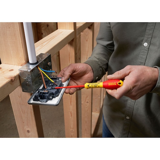 Photo of STANLEY XTHT0-62692 insulated screwdriver in use on electrical outlet wiring, close-up.