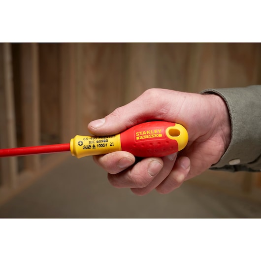 Photo of STANLEY XTHT0-62692 insulated screwdriver with red and yellow handle held in hand.