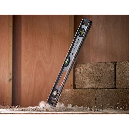 STANLEY XTHT1-42131 spirit level tool in action, three vials, silver and black, construction setting.